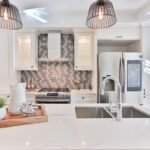Built-in library wall with white cabinetry, open shelves, books, and brass picture lights