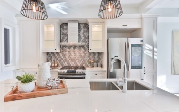 Built-in library wall with white cabinetry, open shelves, books, and brass picture lights