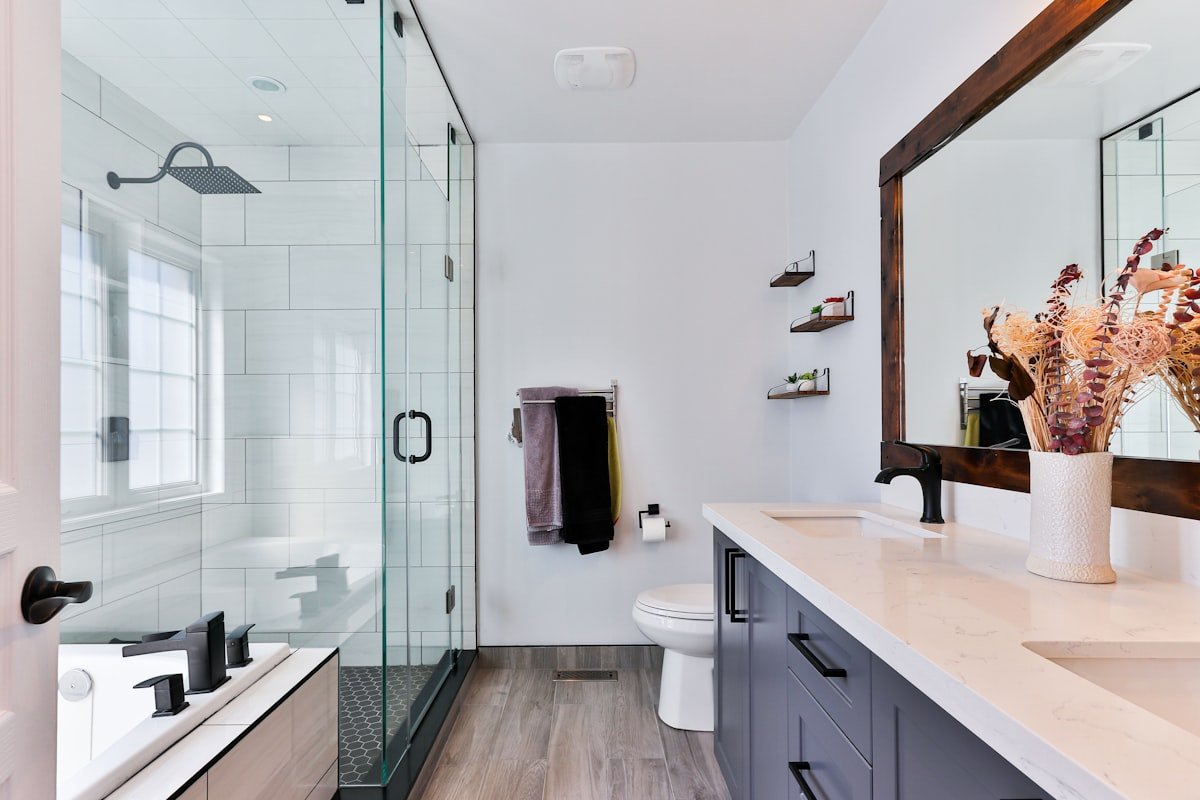 Neatly organized bathroom vanity with glass jars, rolled towels, and plant